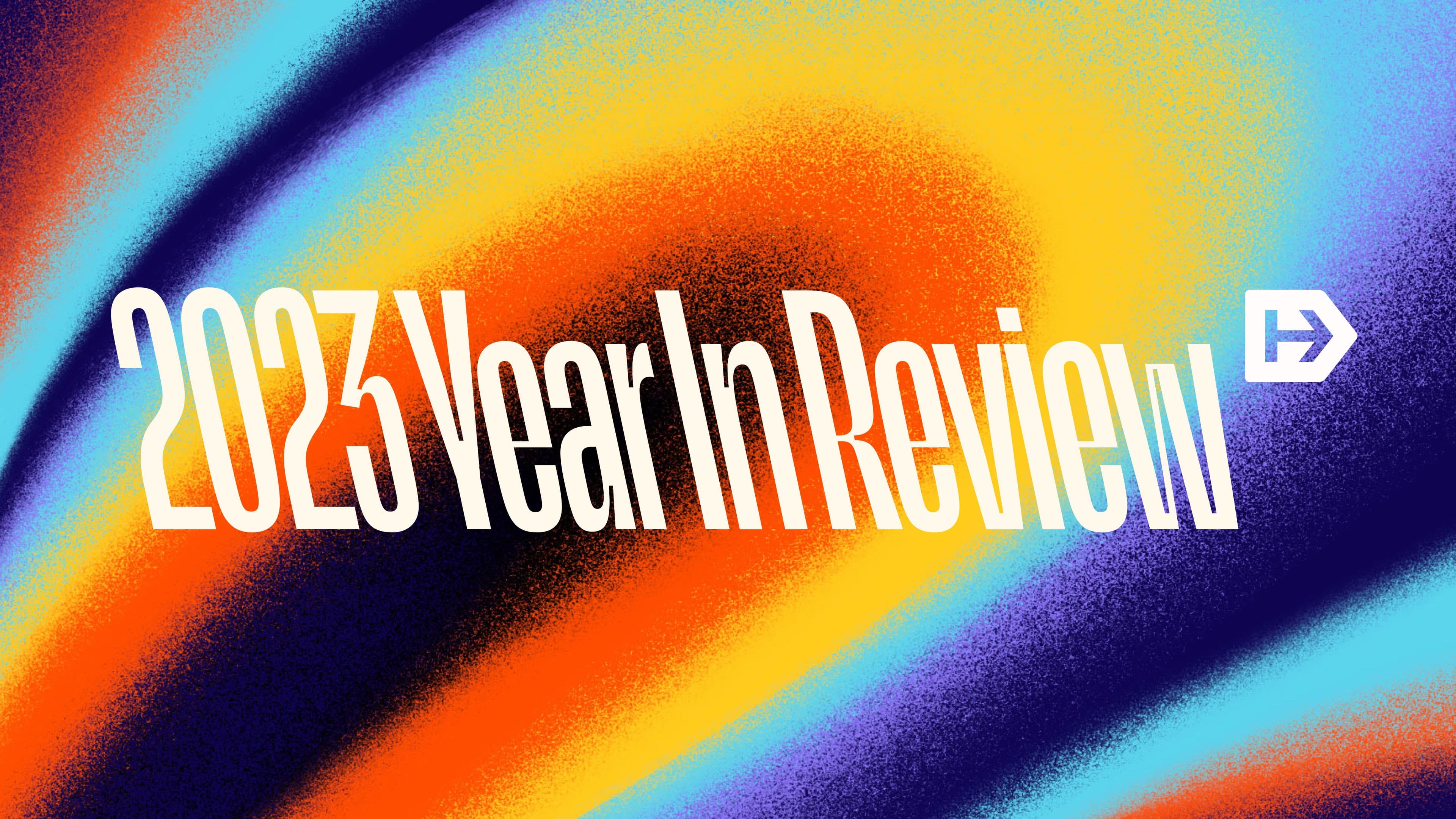Text "2023 Year In Review" in bold, white letters overlays a vibrant, swirling background of blue, orange, and yellow gradients that create a dynamic, eye-catching effect. An arrow icon is placed to the right of the text.