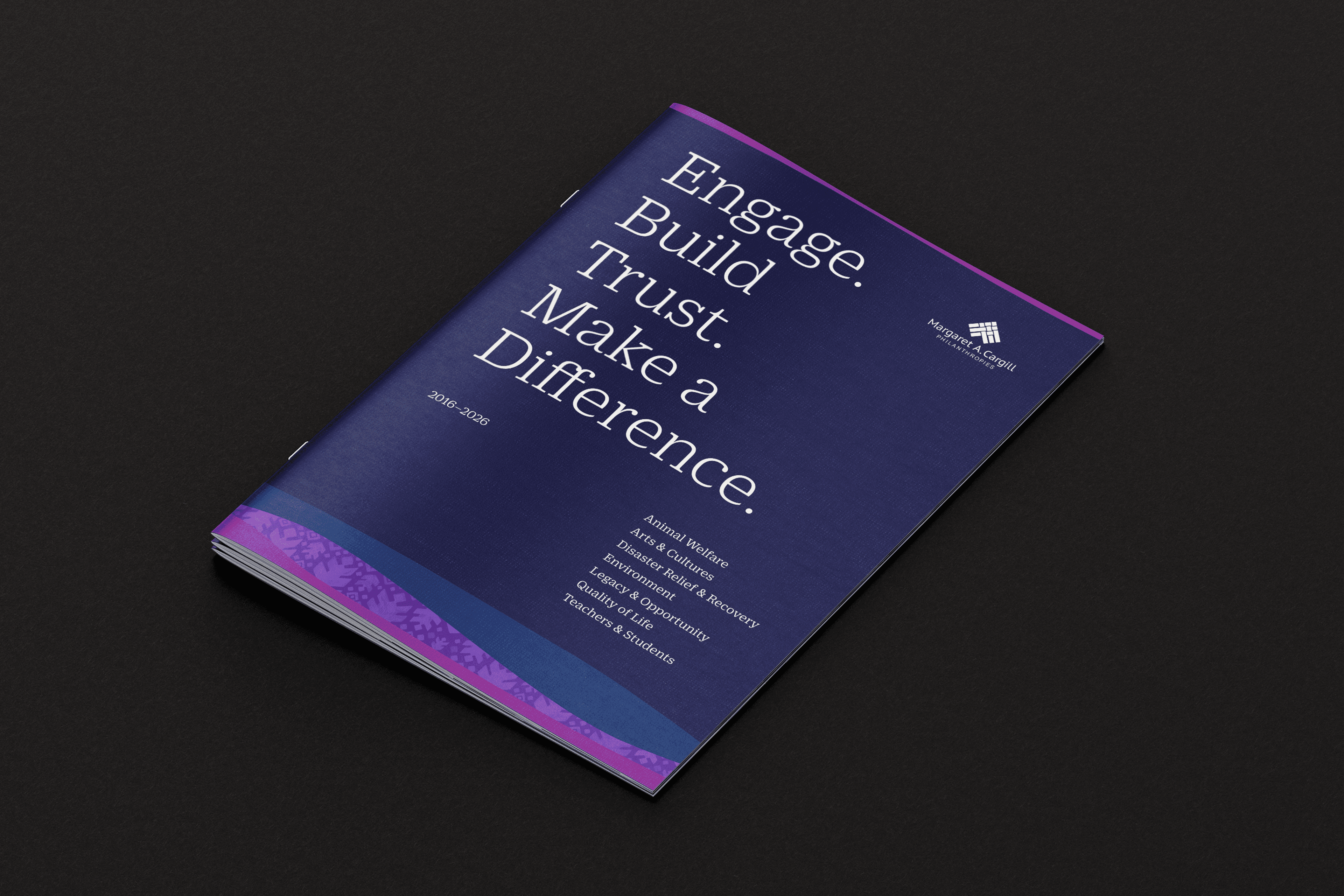A booklet with a dark blue cover lies on a black surface. The cover reads, "Engage. Build Trust. Make a Difference. 2021–2022" and lists values below, with the Hawaiian Electric logo in the corner. Purple patterns decorate the bottom edge.